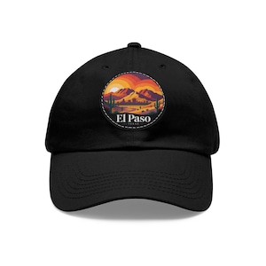 May include: Black baseball cap featuring a circular patch with a desert landscape scene. The patch includes mountains, cacti, and a sunset with the text "El Paso Texas". The cap has a curved brim and an adjustable strap.
