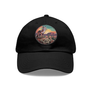 May include: Black baseball cap featuring a circular patch with a coyote illustration, desert landscape, and the text "EL PASO TEXAS." The patch has a colorful design with a sunset and cacti. The cap has a curved brim and an adjustable strap.