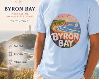 Camiseta con ilustración costera de Byron Bay, Australia: Faro, velero y playa.