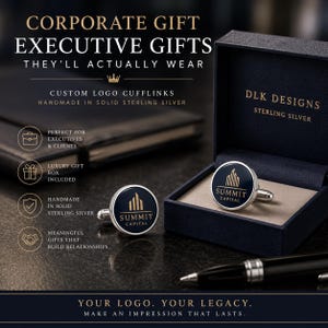 May include: A pair of round sterling silver cufflinks featuring a dark blue inlay with the gold-colored Summit Capital logo. One cufflink rests inside a navy blue presentation box labeled DLK Designs, while the other sits on a dark surface.