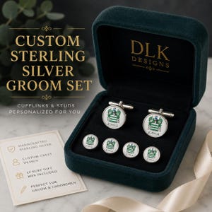 May include: A set of sterling silver cufflinks and studs featuring a custom crest design, presented in a dark green velvet box. The set includes two circular cufflinks and four matching studs, each displaying a detailed green and white heraldic emblem.