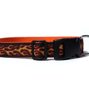 May include: A black dog collar with an orange and yellow flame design. The collar has a black plastic buckle and a silver metal D-ring.