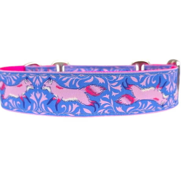 May include: A blue dog collar with a pink interior and silver hardware. The collar features a repeating pattern of pink foxes running across a blue background with a floral design. The collar is approximately 1 inch wide.