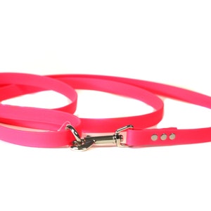 May include: A bright pink dog leash with a silver clip and three silver dots.