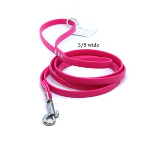 Op de afbeelding: Een felroze hondenriem met een zilveren clip en een breedte van 3/8 inch. De riem is opgerold op een witte achtergrond.