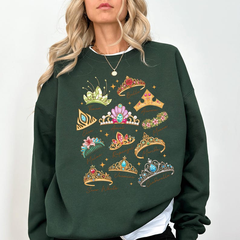A woman wearing a green sweatshirt with a design of various crowns and tiaras printed on it.