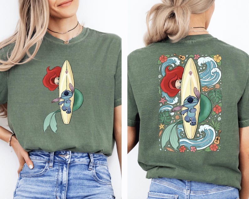 A woman wearing a green t-shirt with a graphic of a mermaid and a surfboard on the back.