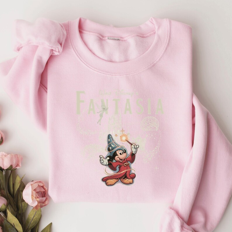 A pink sweatshirt with a Disney-themed graphic of Mickey Mouse and a wizard on it.