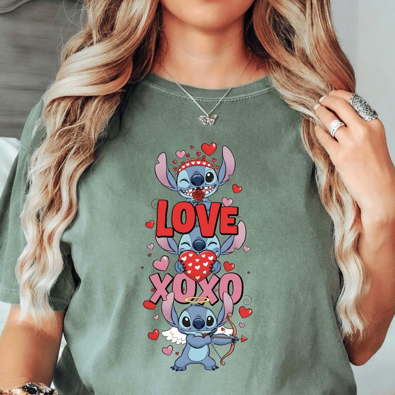 A woman wearing a green t-shirt with a graphic design featuring a cartoon character and the text "LOVE XO XO" surrounded by hearts.