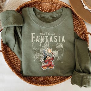 A green t-shirt with a Disney-themed graphic and text, placed in a woven basket.