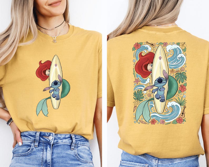 A woman wearing a yellow t-shirt with a graphic of a mermaid and a surfboard on the back.