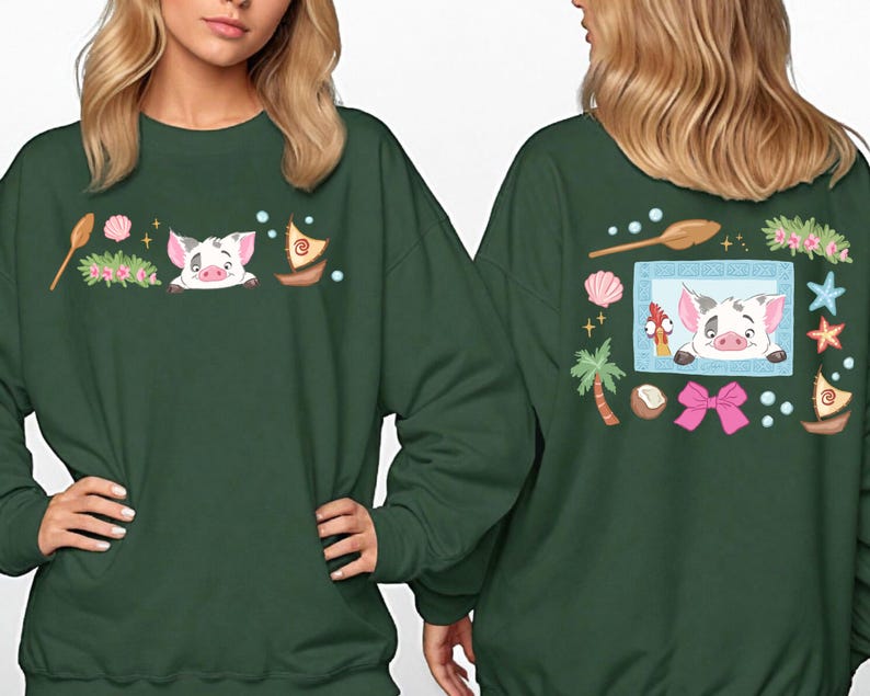 two women wearing green sweatshirts with colorful and whimsical designs, including a pig, flowers, and other decorative elements.