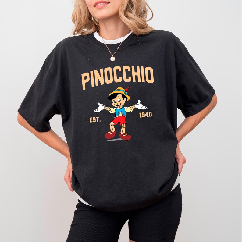 May include: Black t-shirt with a graphic of Pinocchio from the 1940 Disney film. The text "PINOCCHIO EST. 1940" is printed on the shirt.