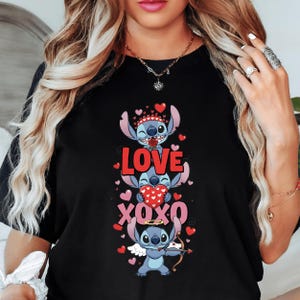 A woman wearing a black t-shirt with a graphic design featuring three cartoon characters and the text "LOVE XO XO" printed on it.