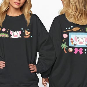 two people wearing black sweatshirts with colorful illustrations of pigs and various objects, such as a boat, palm tree, starfish, and a bow.