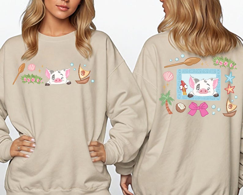 two women wearing beige sweatshirts with colorful illustrations of cartoon pig characters and various tropical elements.