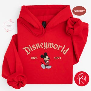 A red hoodie with the text "Disneyworld EST. 1971" and a Mickey Mouse graphic, along with a red embroidered logo and a red circle with the word "Red".