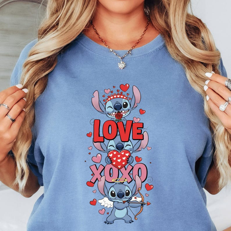 A woman wearing a blue t-shirt with a graphic design featuring a cartoon character and the text "LOVE XOXO".