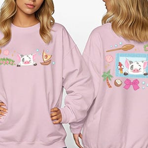 two women wearing pink sweatshirts with cartoon pig designs and various decorative elements.