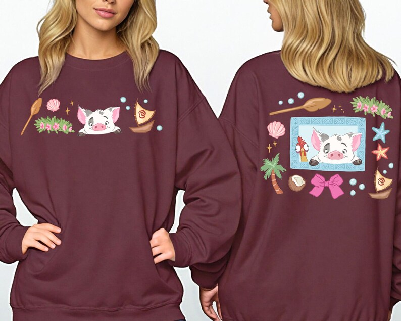 two women wearing burgundy sweatshirts with colorful and whimsical designs, including a pig, flowers, and other decorative elements.