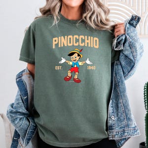 May include: A green t-shirt with a cartoon image of Pinocchio, the text "PINOCCHIO", "EST. 1940", and a yellow and orange color scheme.