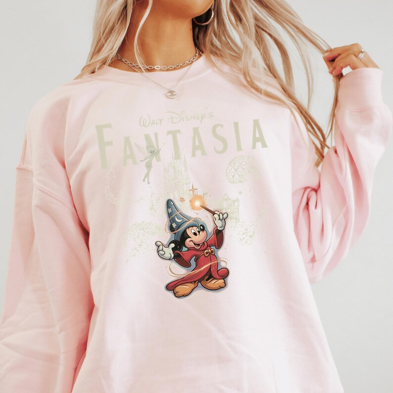 A woman wearing a pink sweatshirt with a Disney-themed graphic of Mickey Mouse and the text "Disney's Fantasia".