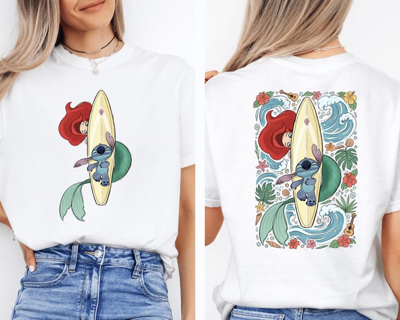 A woman wearing a white t-shirt with a colorful graphic of a mermaid and a surfboard on the back.