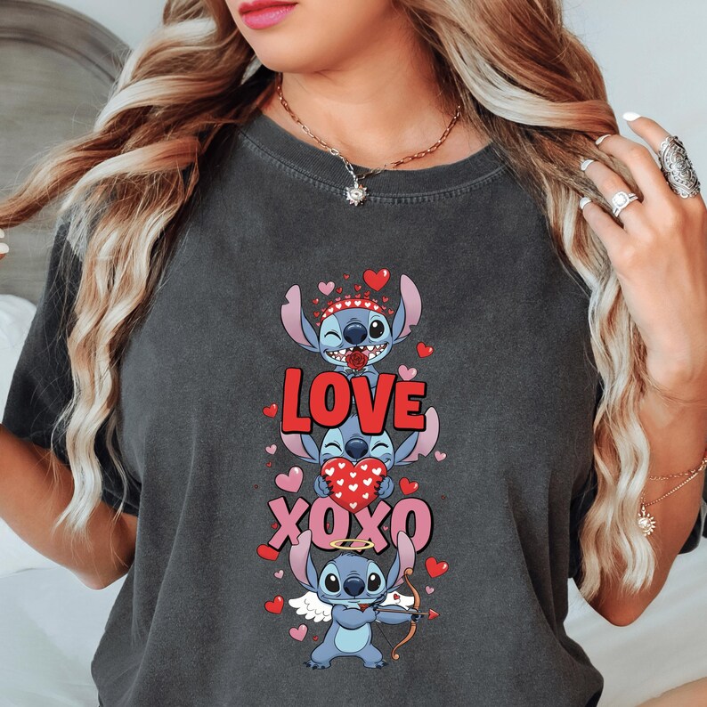 A woman wearing a gray t-shirt with a graphic design featuring a cartoon character and the text "LOVE xOXO" surrounded by hearts.
