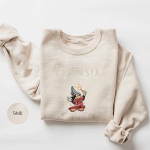 A beige sweater with a Disney character printed on it, along with the text "FANTASIA" printed below the character.