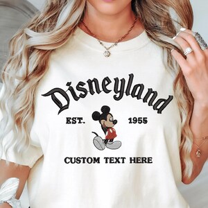 A white t-shirt with a Mickey Mouse graphic and text that says "Disneyland EST. 1955 CUSTOM TEXT HERE".