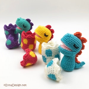 May include: Four crocheted dinosaur toys in different colors, each with a matching egg. The dinosaurs are yellow, blue, green, and purple. The eggs are white with blue, red with yellow, red with yellow, and purple with green polka dots.