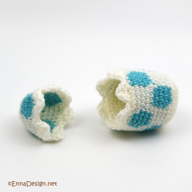 May include: A crocheted egg with a blue and white pattern is split in half, revealing the inside of the egg.