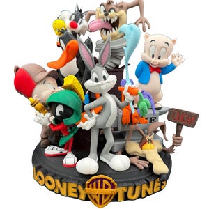 Peut inclure: Figurine multicolore représentant les personnages de Looney Tunes, dont Bugs Bunny et Daffy Duck. La base noire porte des lettres dorées et un logo doré en forme de bouclier. Les personnages sont dans diverses poses.