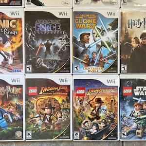 May include: A collection of Wii video game cases featuring titles like "Sonic and the Secret Rings," "Star Wars: The Force Unleashed," "Harry Potter," and Lego-themed games. The cases display colorful graphics and game titles.