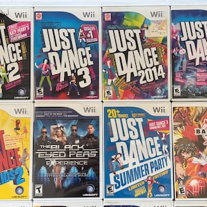 May include: A collection of Wii video game cases featuring the "Just Dance" series, including "Just Dance 2," "Just Dance 3," "Just Dance 2014," and "Just Dance 2018." Other titles include "Just Dance Kids 2," "The Black Eyed Peas Experience," and "Bakugan."