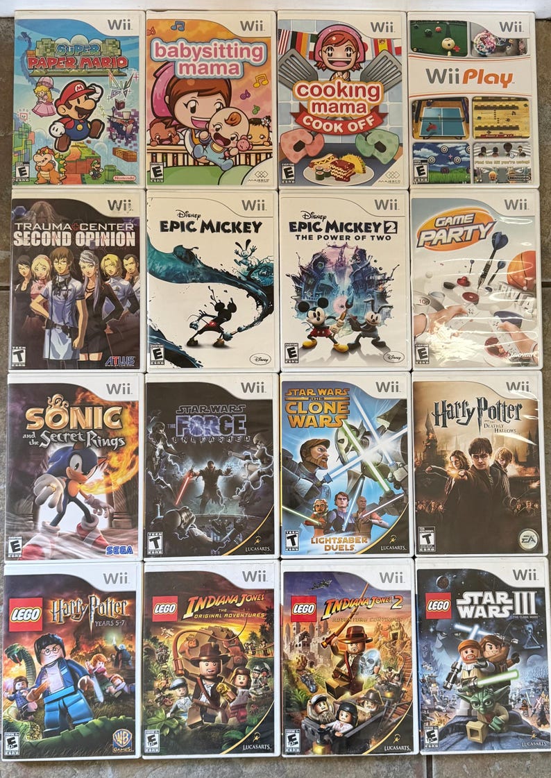 May include: A collection of Wii video game cases, featuring titles like "Super Paper Mario," "Epic Mickey," and "Lego Star Wars III." The game covers display colorful graphics and game titles.