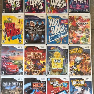 May include: A collection of Wii video game cases, including titles like "Just Dance 2," "Just Dance 3," and "Call of Duty 3." The cases feature colorful graphics and game titles. The games are from various genres.