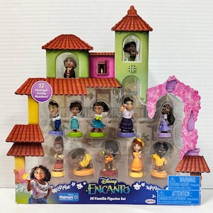 May include: A Disney Encanto Mi Familia figurine set featuring 12 Madrigal family members. The set includes miniature figurines of characters from the movie, displayed in a colorful, multi-level house structure. The packaging includes the Walmart and Disney logos.