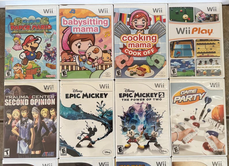 May include: A collection of Wii game cases, featuring titles like "Super Paper Mario," "Babysitting Mama," "Cooking Mama Cook Off," and "Wii Play." Other games include "Trauma Center: Second Opinion," and "Epic Mickey."