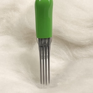 May include: A hair pick featuring a smooth, rounded, bright green handle and four long, thin, dark gray tines. The tool is designed for styling and detangling hair, with a sleek, minimalist construction that emphasizes the contrast between the vibrant green top and the neutral gray metal prongs.