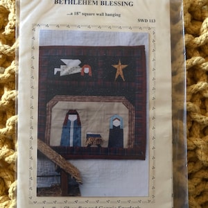 Può includere: Un modello per un'appendice murale quadrata da 45,7 cm intitolata "Bethlehem Blessing" di Teri Chandler e Connie Spurlock. Il modello presenta una scena della natività con una stella, un angelo e figure di Maria, Giuseppe e il bambino Gesù.