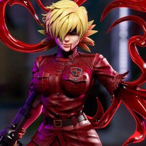 May include: A detailed figurine of a character with spiky blonde hair and red eyes, wearing a dark red military-style uniform with a badge. The figure has a determined expression and is surrounded by red, claw-like appendages.