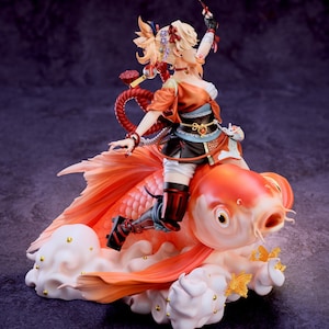 May include: A figurine of a female character from the video game Genshin Impact, riding a large, orange goldfish. The character is wearing a red and black outfit with a long, flowing red scarf. The goldfish is sitting on a white cloud with gold accents. The figurine is made of high-quality plastic and is very detailed.