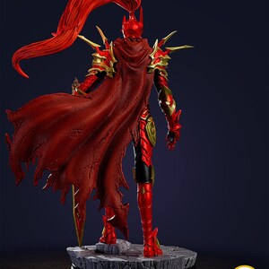 May include: A red and gold figurine of a warrior, viewed from the back. The figure is posed on a stone-like base. The warrior wears a red cape and armor with gold accents. The text "PATREON.COM/BEEFIGURES" is visible.