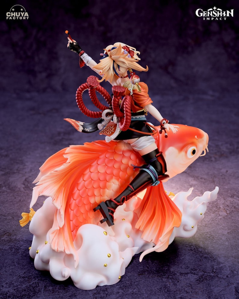 May include: A figurine of a character from the video game Genshin Impact, riding a large orange and red fish. The character is wearing a red and white outfit with a long, flowing blonde ponytail. The fish is on a white cloud base with gold accents. The figurine is made by Chuya Factory.