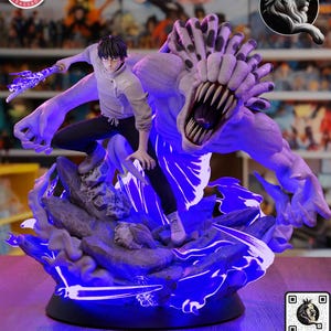 May include: A detailed action figure featuring a character in a gray top and black pants, battling a large, monstrous figure with sharp teeth. The base has blue glowing accents. The figure is on a shelf with other figures.