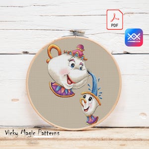 Può includere: Un telaio da ricamo a punto croce con una teiera dei cartoni animati che versa acqua in una tazza da tè. La teiera e la tazza da tè hanno facce sorridenti e sono decorate con accenti viola, rosa e oro. Il testo "Vicky Magic Patterns" è in basso.