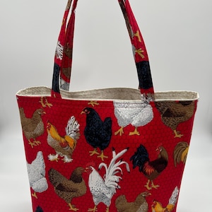 May include: Red tote bag with a chicken print. The bag has two handles and a white lining.