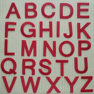 May include: Red felt letters of the alphabet, A through Z, on a light green background with a leaf pattern.