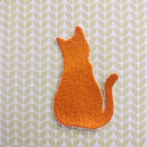 May include: Orange felt cat applique, perfect for adding a touch of whimsy to crafts and projects.